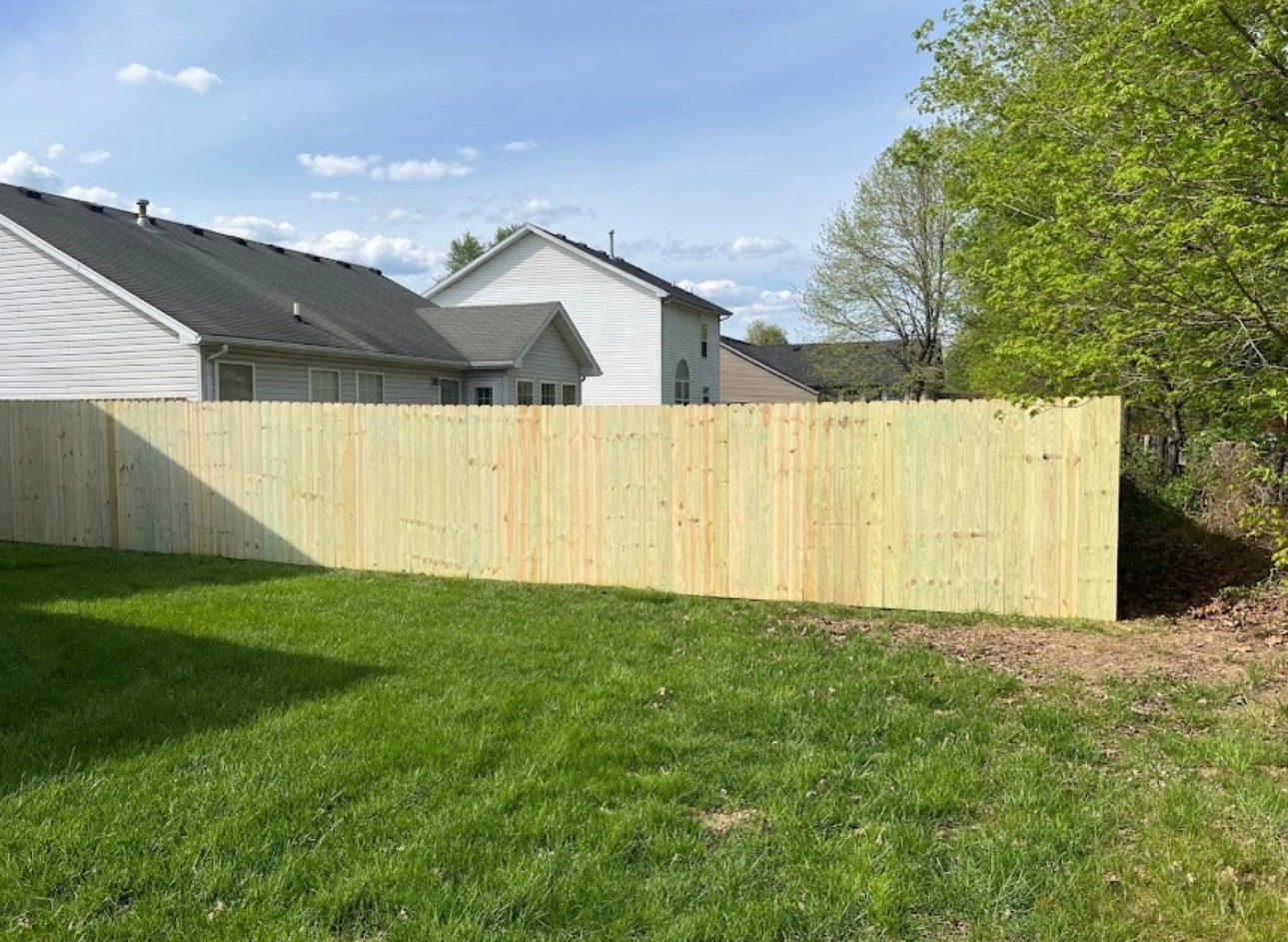 New wood privacy fence enclosing a green backyard, installed by Prime Fence